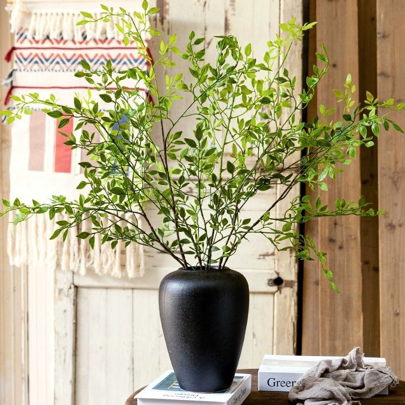 Elegante Glasvase mit lebensechter Grünpflanzenanordnung