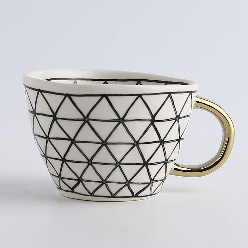 Tasse mit abstraktem geometrischen Muster und goldenem Henkel
