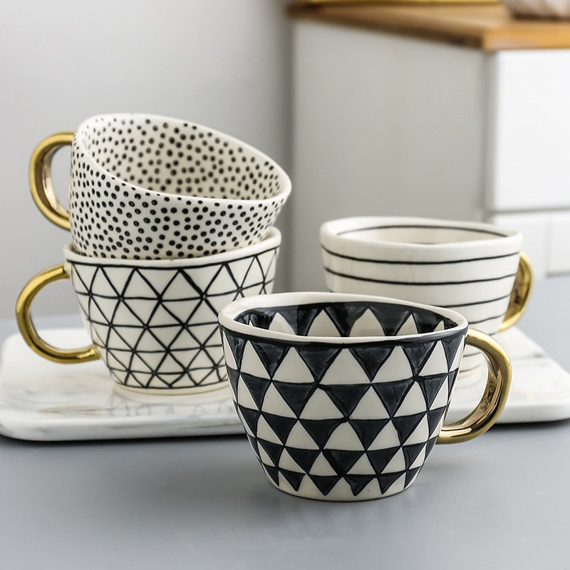 Tasse mit abstraktem geometrischen Muster und goldenem Henkel
