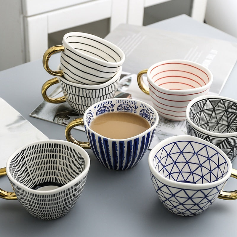 Tasse mit abstraktem geometrischen Muster und goldenem Henkel