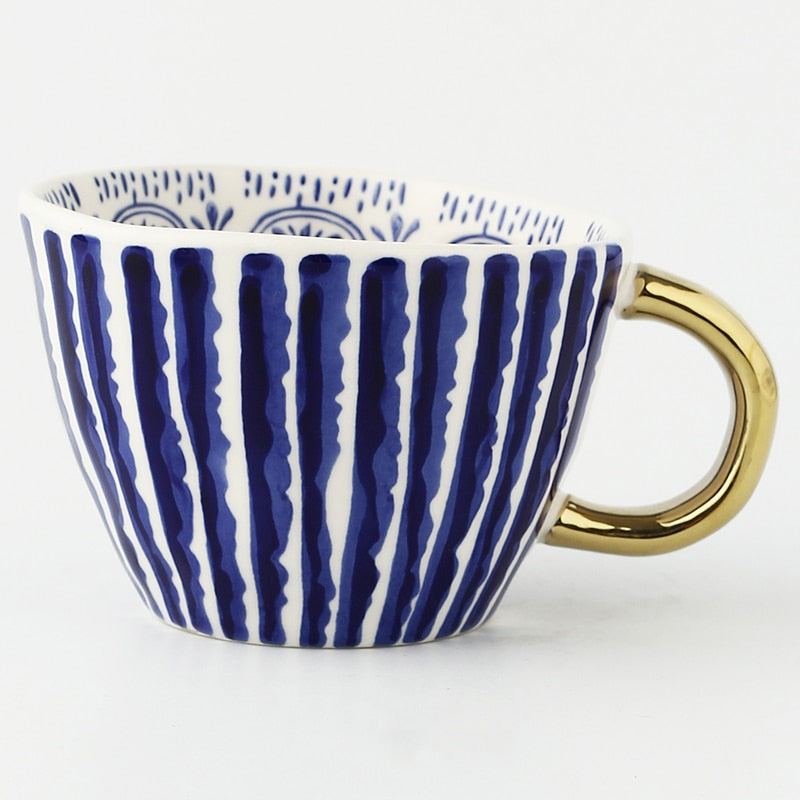 Tasse mit abstraktem geometrischen Muster und goldenem Henkel