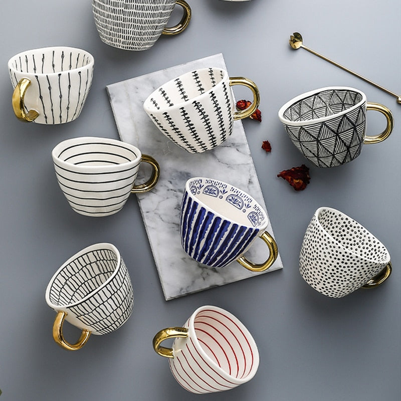 Tasse mit abstraktem geometrischen Muster und goldenem Henkel