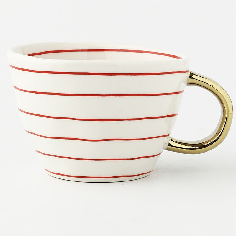 Tasse mit abstraktem geometrischen Muster und goldenem Henkel