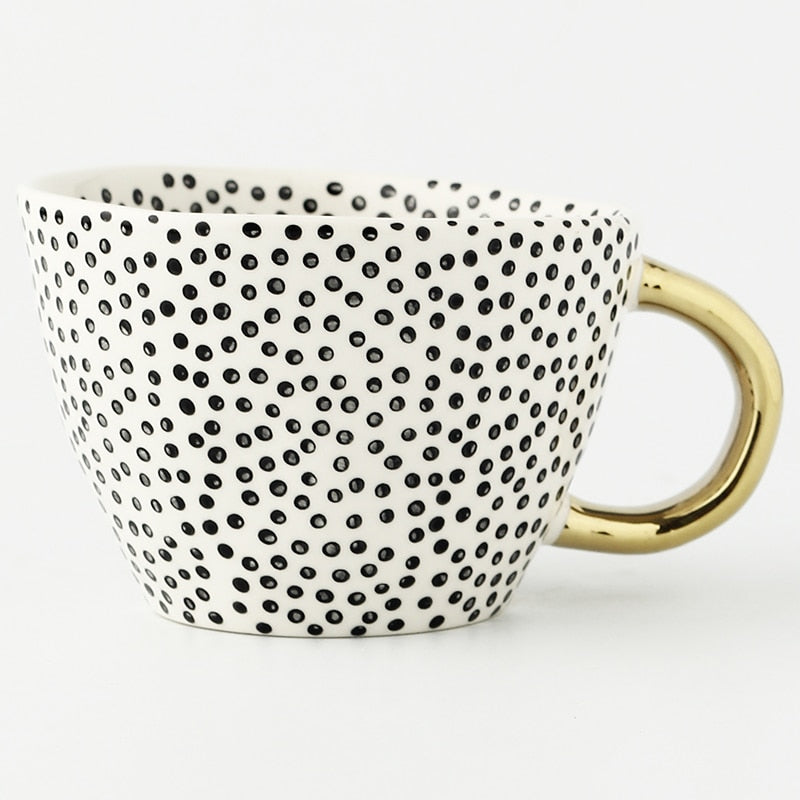 Tasse mit abstraktem geometrischen Muster und goldenem Henkel