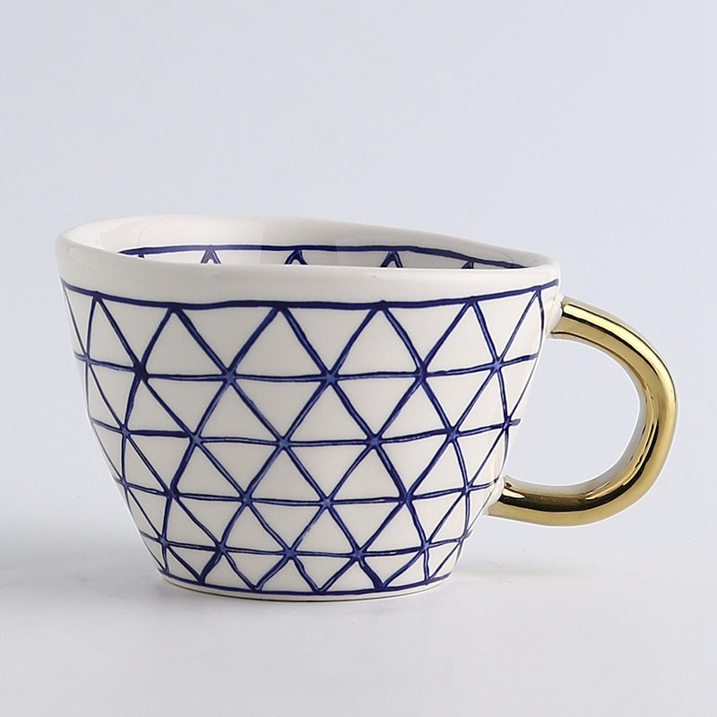 Tasse mit abstraktem geometrischen Muster und goldenem Henkel