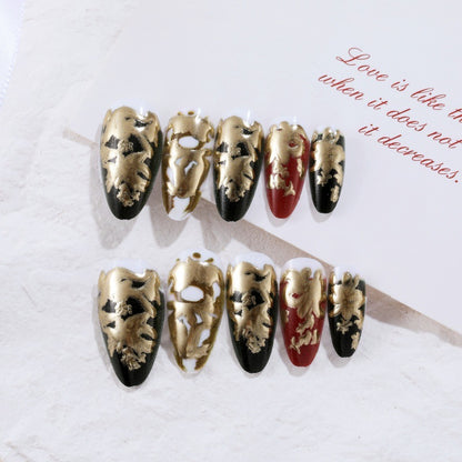 Elegante Kunstnägel mit Gold- und Schwarzmuster Brehn