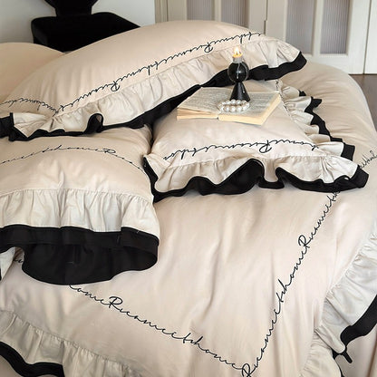 Luxuriöse Baumwoll-Satin-Bettwäschegarnitur mit Volant, kontrastierender Paspel und kalligrafischer Stickschrift