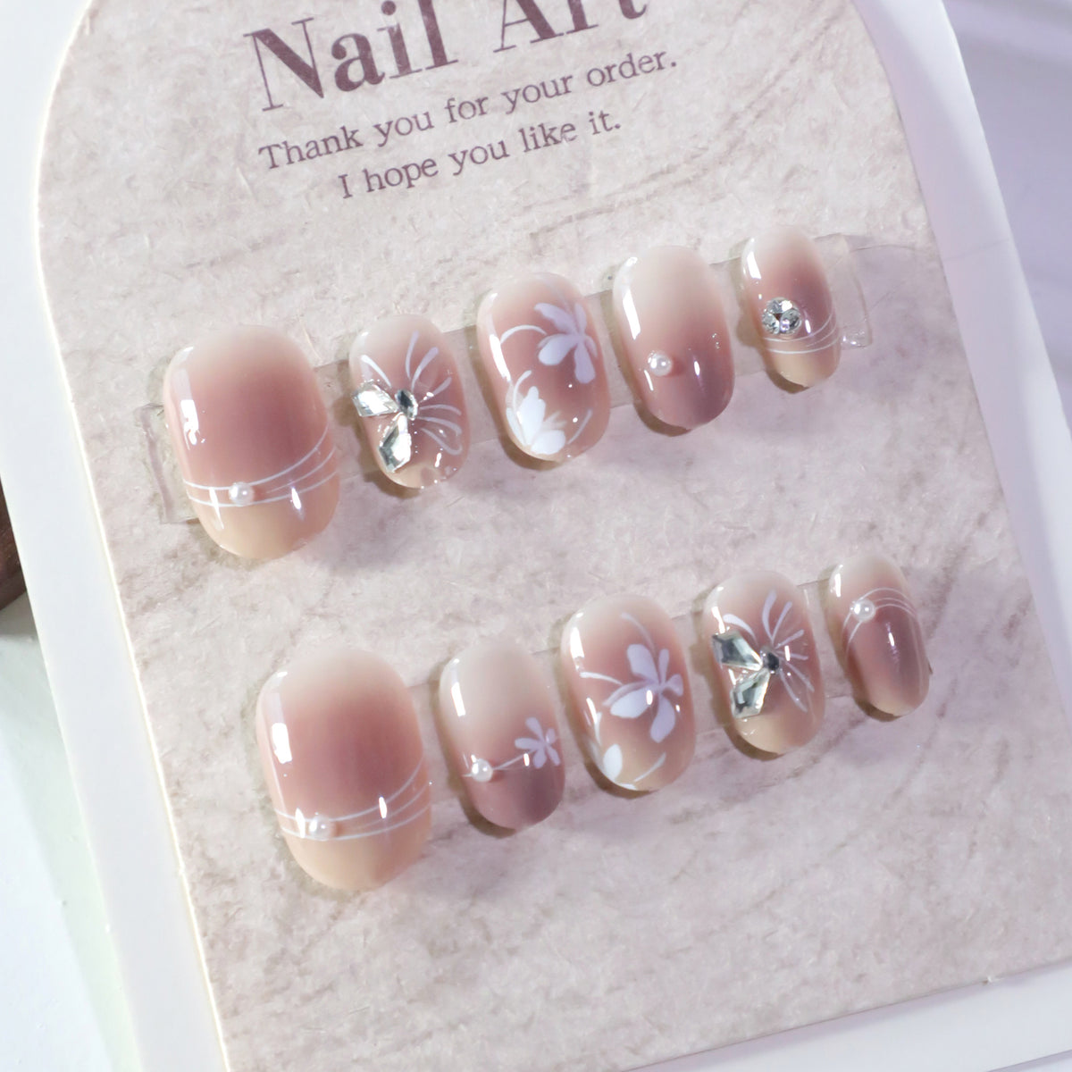 Kunstvolle Nagelgestaltung mit floralem Design und Glitzerakzenten Brehn