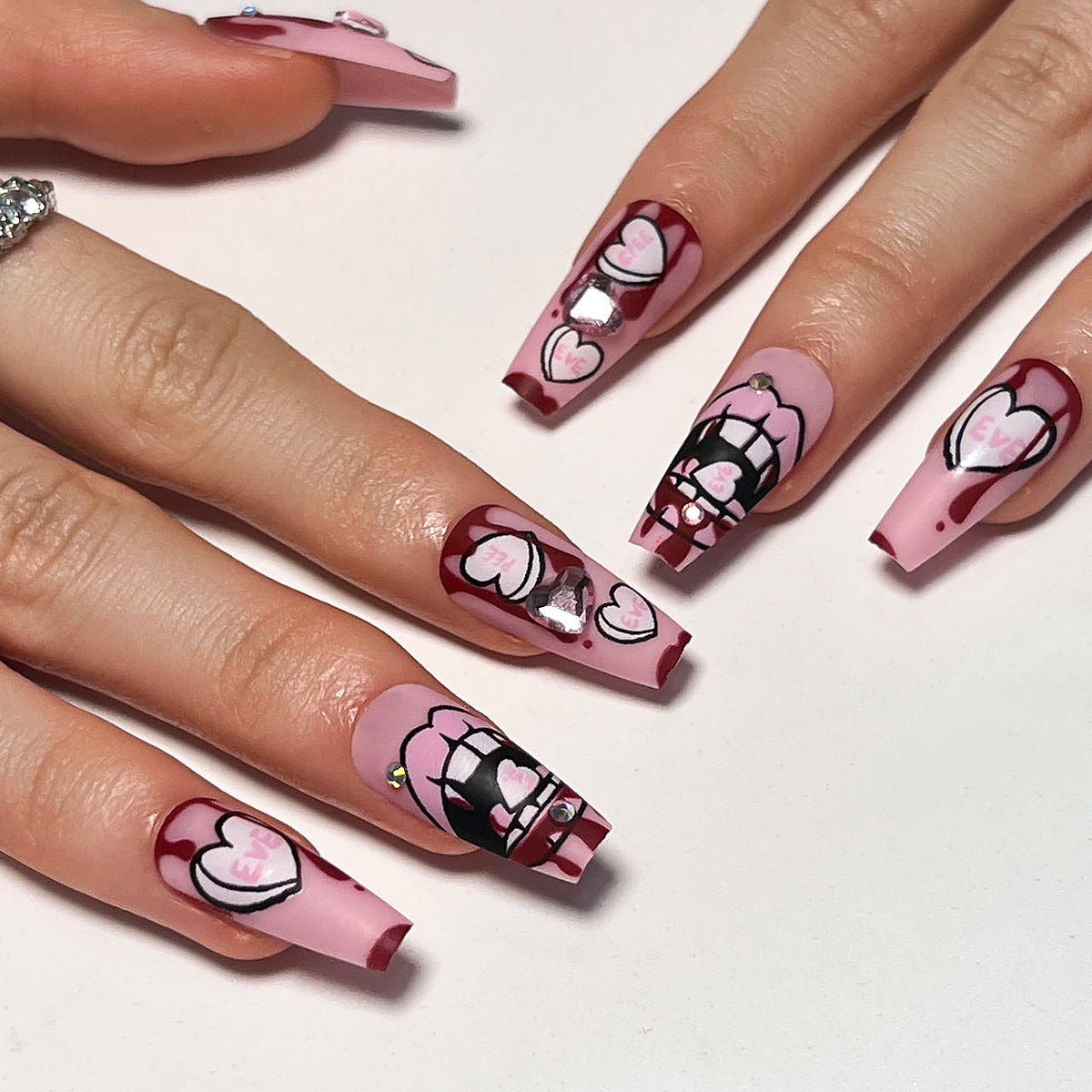 Kunstvolle Stiletto-Nägel mit Herzen und Glitzerakzenten Brehn