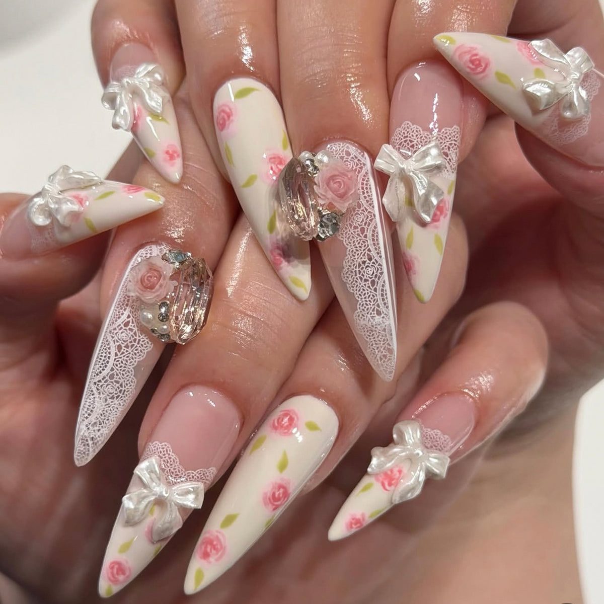 Kunstvolle Stiletto-Nägel mit floralen Akzenten und Glitzerakzenten Brehn