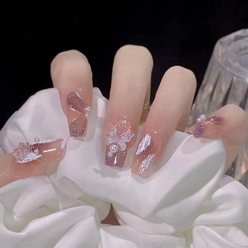 Kunstvolle Nagelkunst mit Schmetterlings- und Perlendetails Brehn