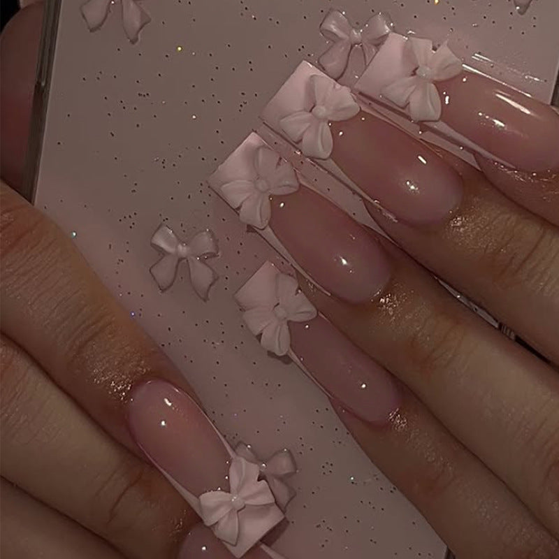 Kunstnagelset mit schimmernden Details und niedlichen Schleifen Brehn