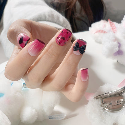 Kunstvolle Nagelverlängerungen mit niedlichen Schleifen- und Herzmotiven Brehn
