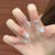 Künstlerisches Press-On-Nageldesign mit floralem und edelsteinbesetztem Akzent Brehn