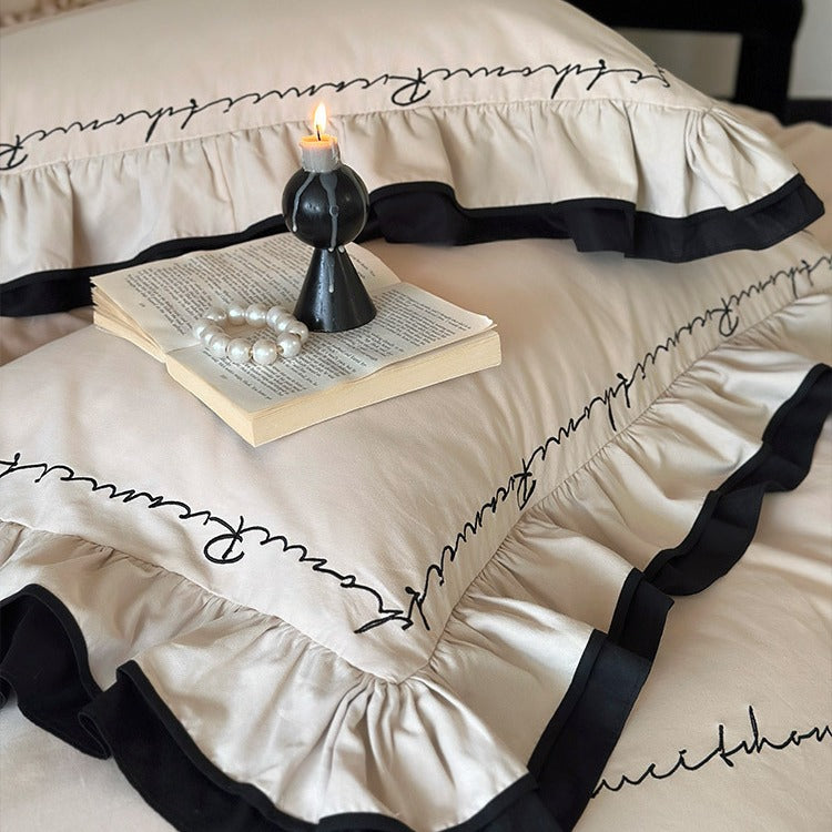 Luxuriöse Baumwoll-Satin-Bettwäschegarnitur mit Volant, kontrastierender Paspel und kalligrafischer Stickschrift