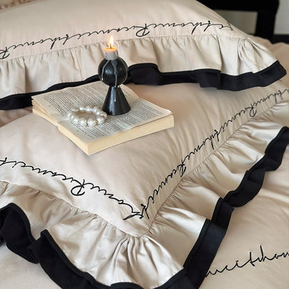 Luxuriöse Baumwoll-Satin-Bettwäschegarnitur mit Volant, kontrastierender Paspel und kalligrafischer Stickschrift