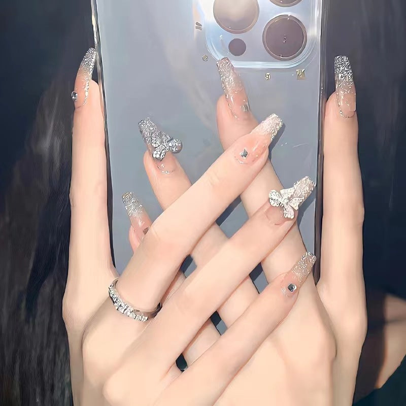 Kunstvolle Nagelkunst mit Schmetterlings- und Perlendetails Brehn