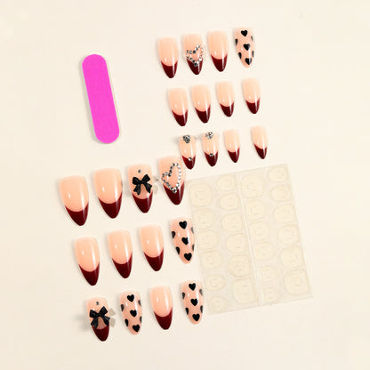 Künstlerische Stiletto-Nagelverlängerungen mit Herz- und Schleifenakzenten Brehn