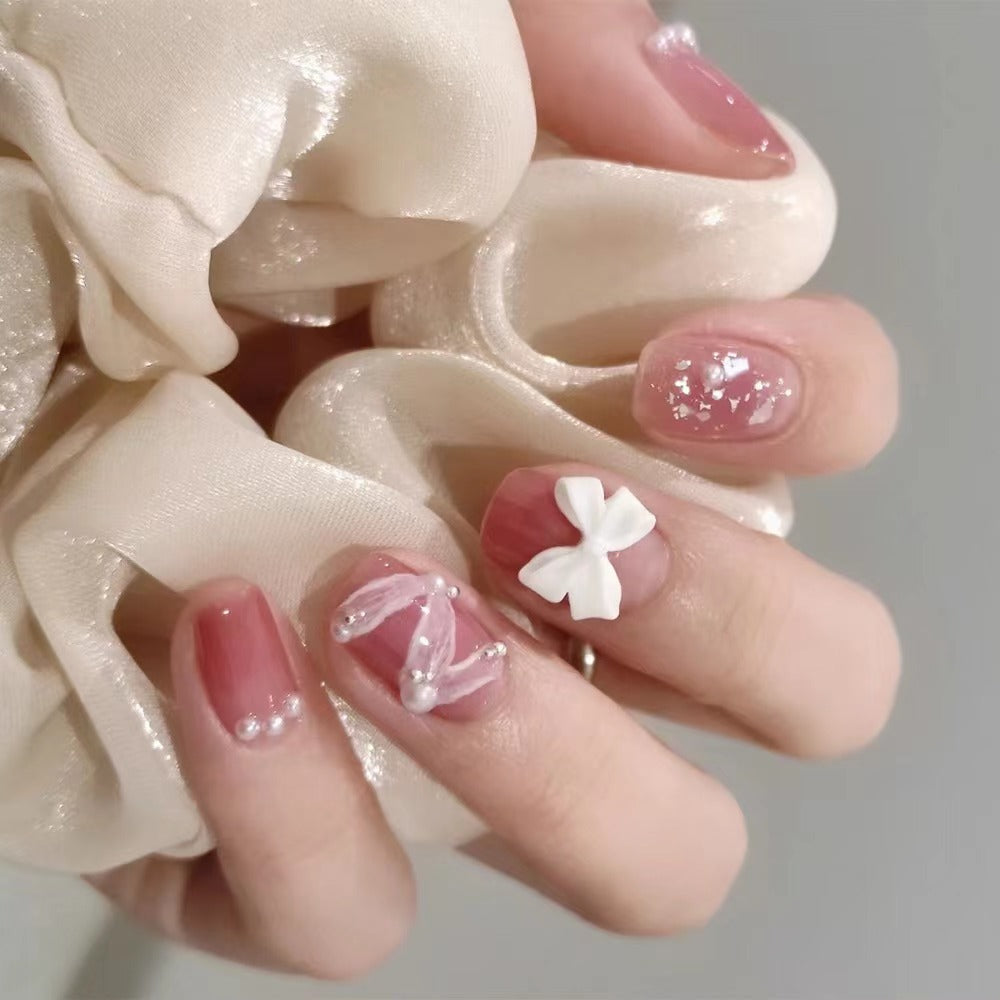 Glamouröse Nagelkunst mit Perlen- und Schleifenakzenten Brehn
