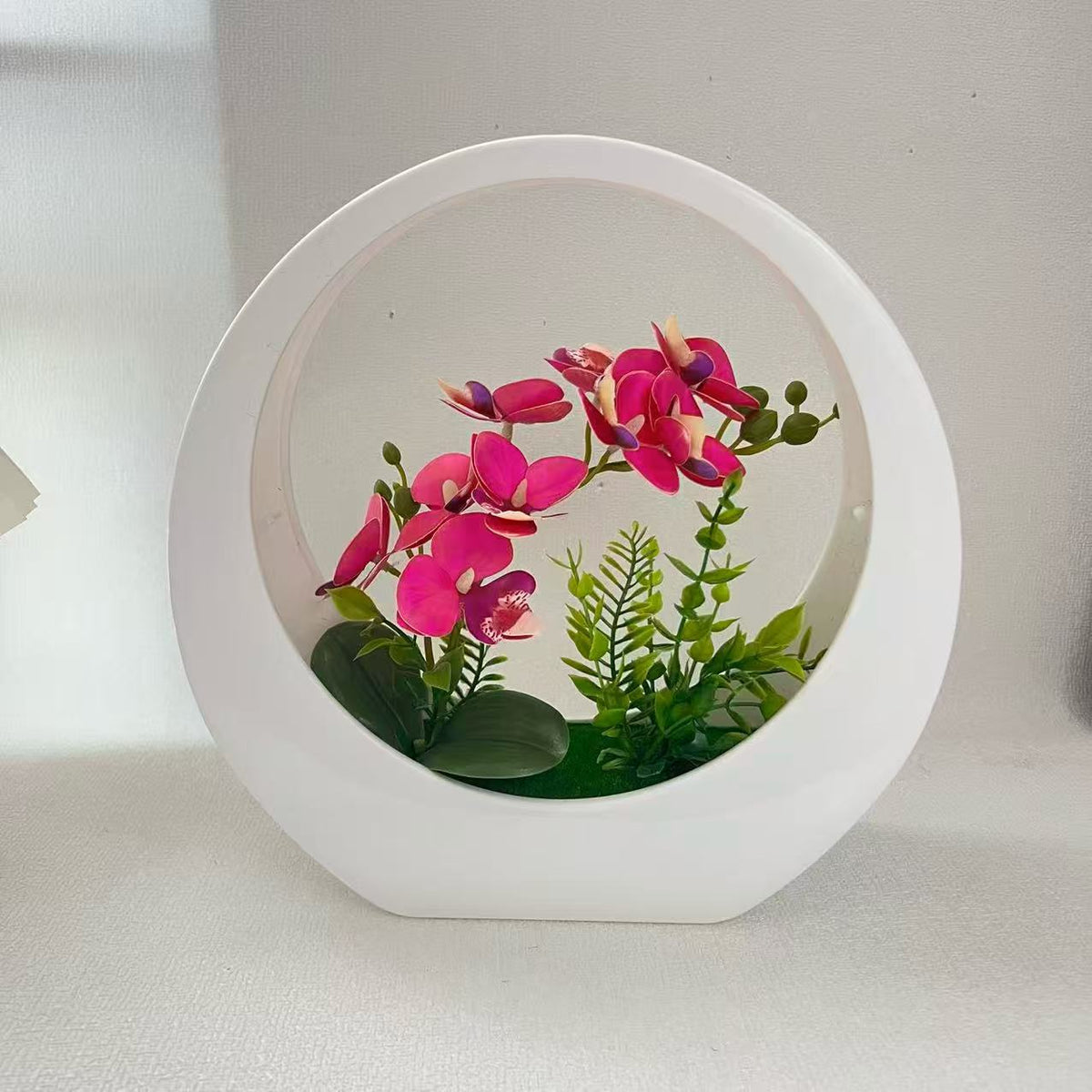 Dekorative Orchideenpflanze in modernem runden Vase