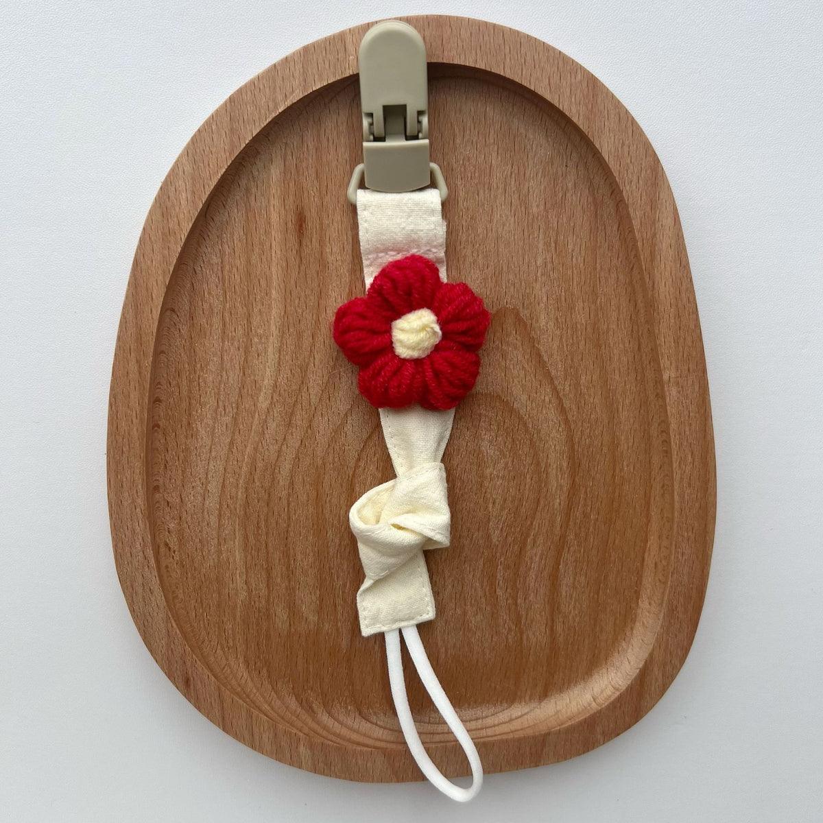 Handgemachter Baumwoll-Schnullerclip mit Gingham-Gurt und gestrickter Blume