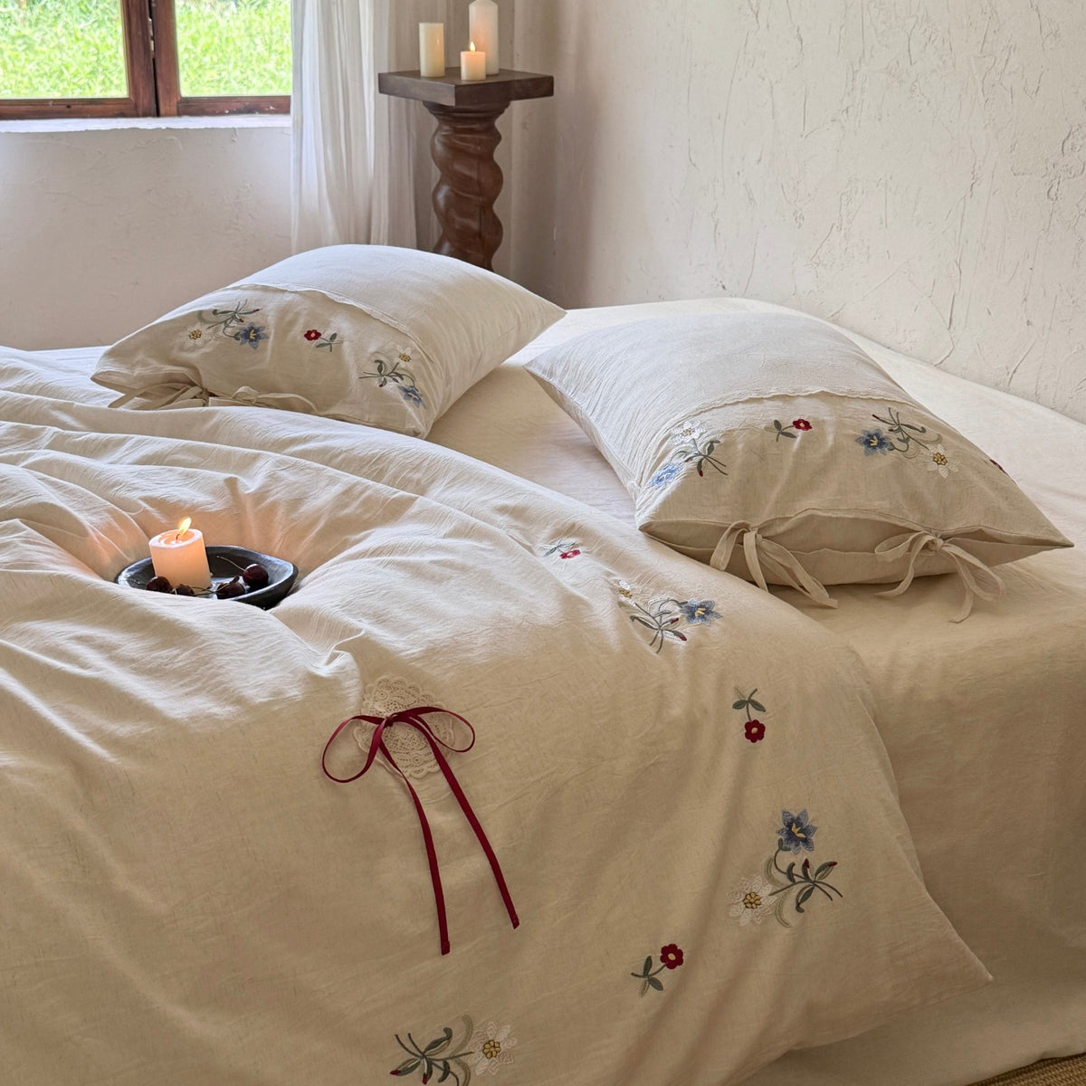 Romantische Leinen-Baumwoll-Bettgarnitur mit zarter Blumenstickerei, Bindeschlaufen und Rundkissen