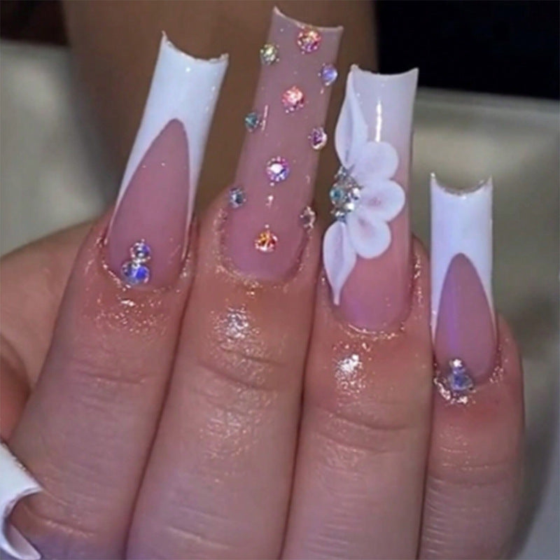 Kunstvolle Stiletto-Nägel mit floralen Akzenten und Strass-Details Brehn