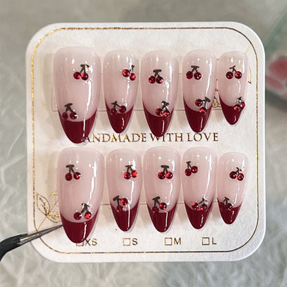 Kunstvolle Stiletto-Nägel mit Kirschmotiven und Glitzerakzenten Brehn
