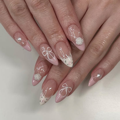 Kunstvolle Nagelkunst mit floralen Details und Schleifenverzierungen Brehn