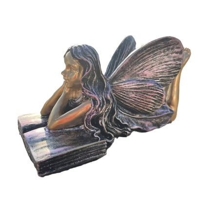 Feenfigurine, die auf Büchern sitzt, Brehn