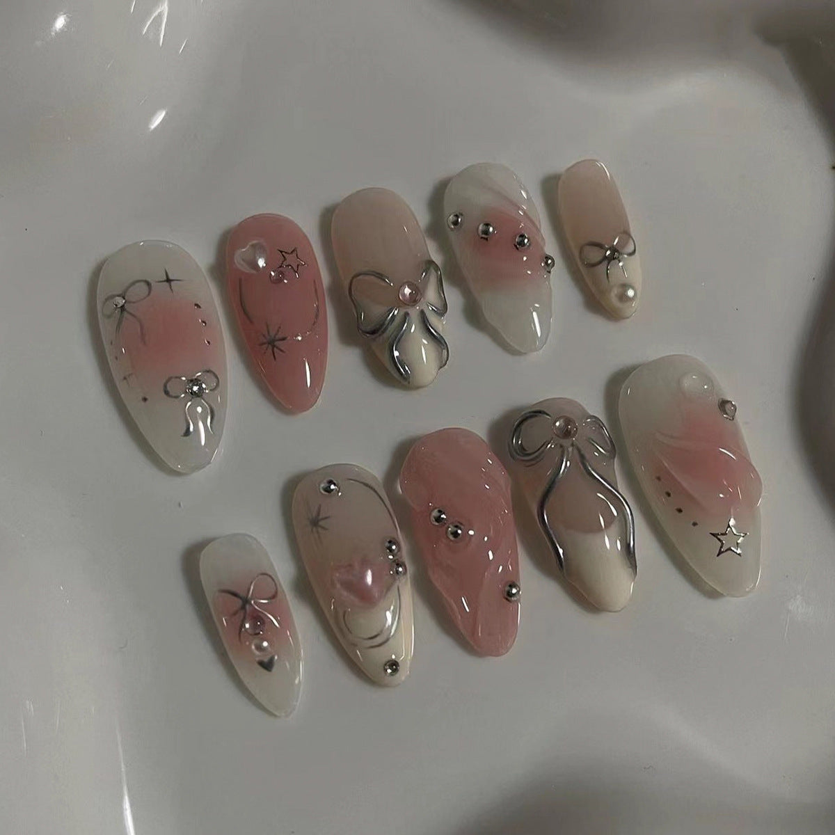 Kunstvolle Nagelspitzen mit Glitzer- und Schleifenmotiven Brehn