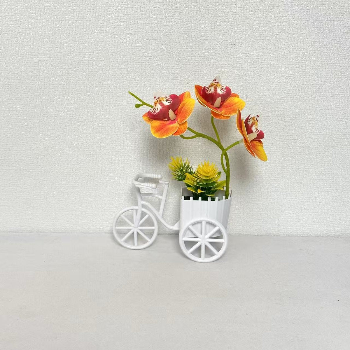 Dekorativer Fahrrad-Blumentopf mit Kunstorchideen-Arrangements für Dekor