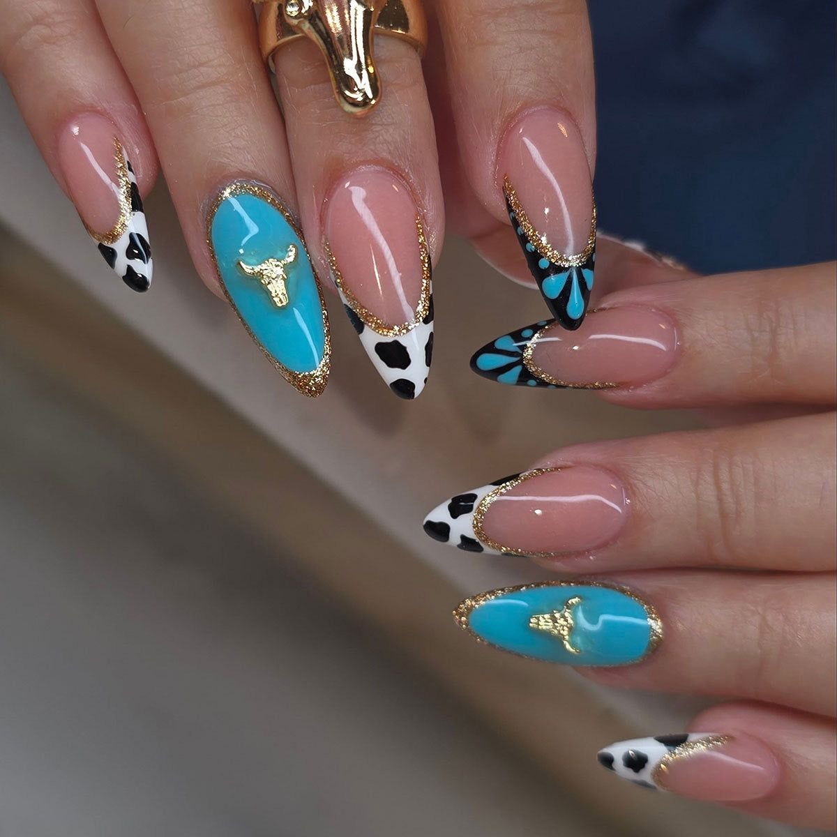 Künstlerische Stiletto-Nagelverlängerungen mit Kuhmotiv und goldenen Akzenten Brehn