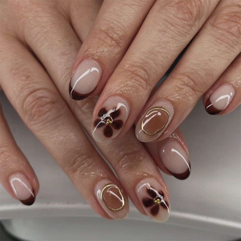 Elegante Nagelkunst mit floralen Akzenten und goldenen Details Brehn