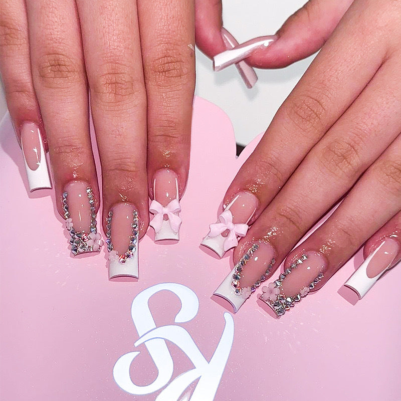 Kunstnagelset mit sorgfältigen Schleifen- und Glitzerverzierungen Brehn