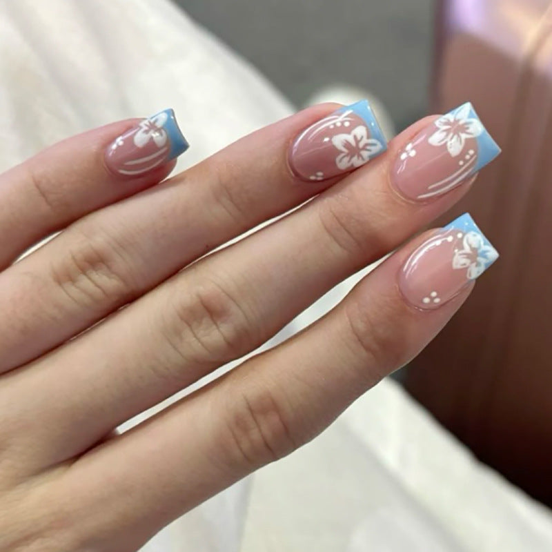 Kunstvolle Nagelkunst mit Blumen-Design und Blauem French Tip Brehn