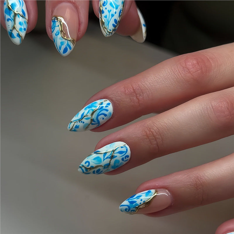 Künstlerisches florales Press-On-Nageldesign mit goldenen Akzenten Brehn