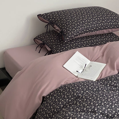 Wendbare Bettwäsche‑Garnitur aus Baumwollsatin mit feinem Blumenallover, kontrastierter Innenseite und dekorativen Schleifen