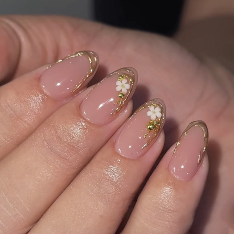 Kunstvolle Nagelgestaltung mit goldenen Akzenten und floralen Details Brehn