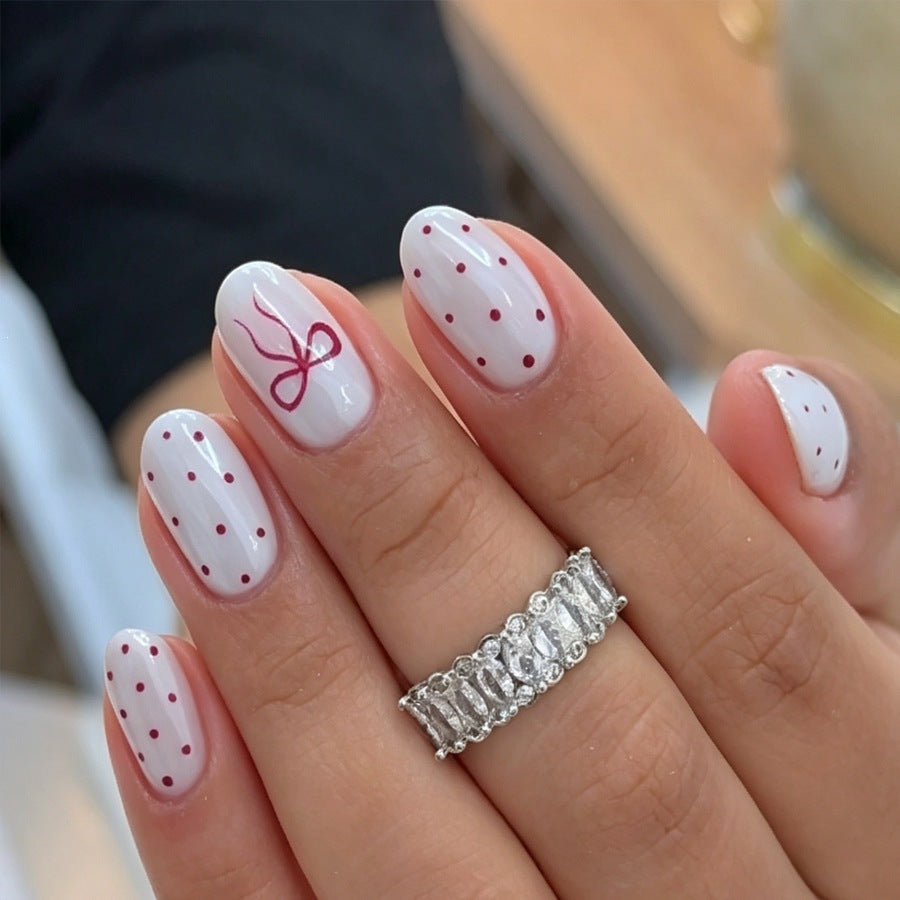 Kunstnagelset mit zarten Punkten und Schleifenmuster Brehn