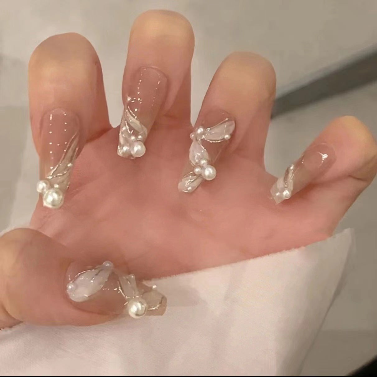 Kunstvolle Nagelkunst mit Schmetterlings- und Perlendetails Brehn