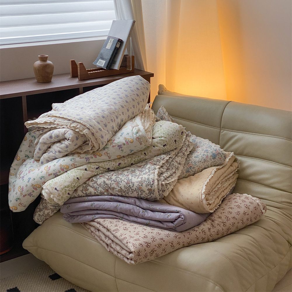 Gesteppte Wohndecke aus Baumwoll‑Mischgewebe mit zartem Blumenmuster und Spitzenkante
