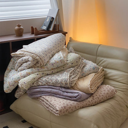 Gesteppte Wohndecke aus Baumwoll‑Mischgewebe mit zartem Blumenmuster und Spitzenkante