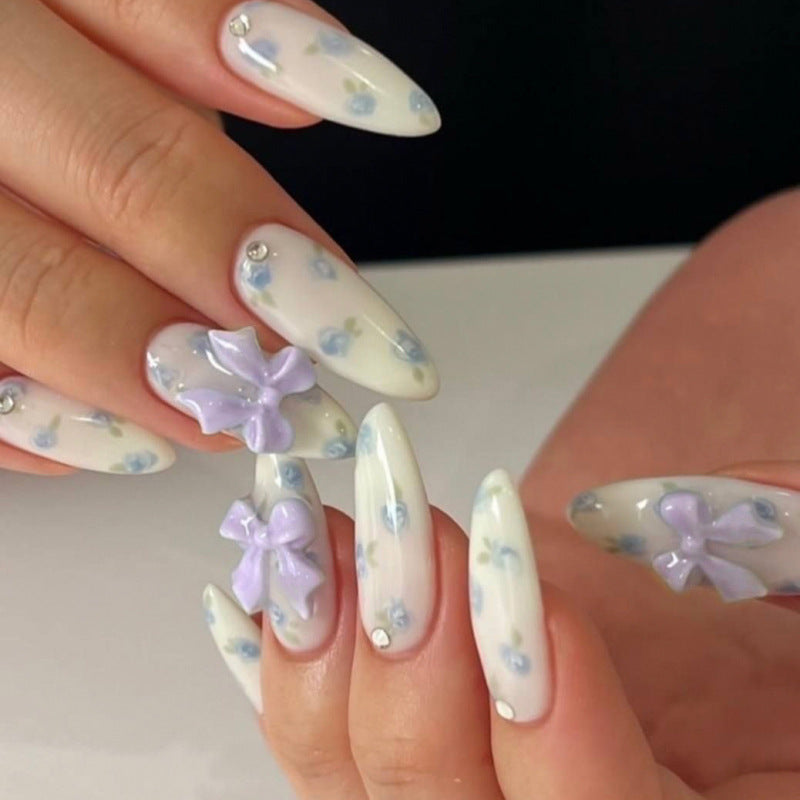 Kunstvolle Stiletto-Nägel mit zarten Blütenmotiven und Glitzerakzenten Brehn
