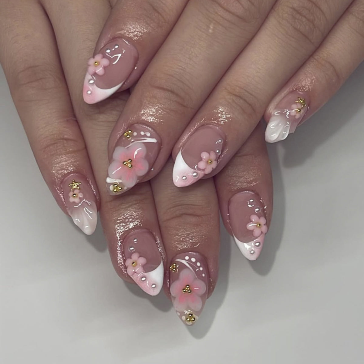 Kunstvolle Nagelverlängerungen mit Blütenmuster und Glitzerakzenten Brehn