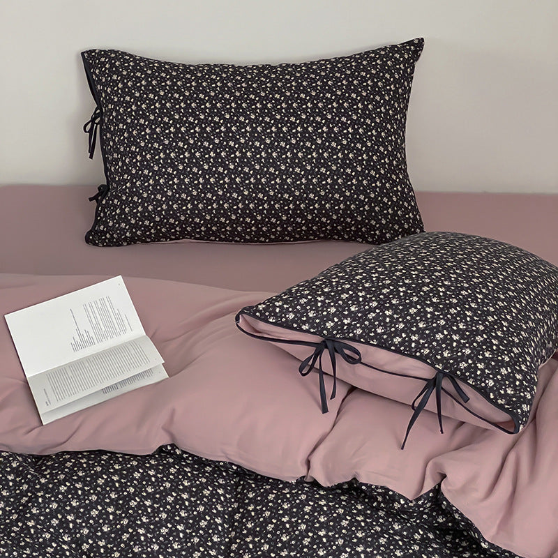 Wendbare Bettwäsche‑Garnitur aus Baumwollsatin mit feinem Blumenallover, kontrastierter Innenseite und dekorativen Schleifen