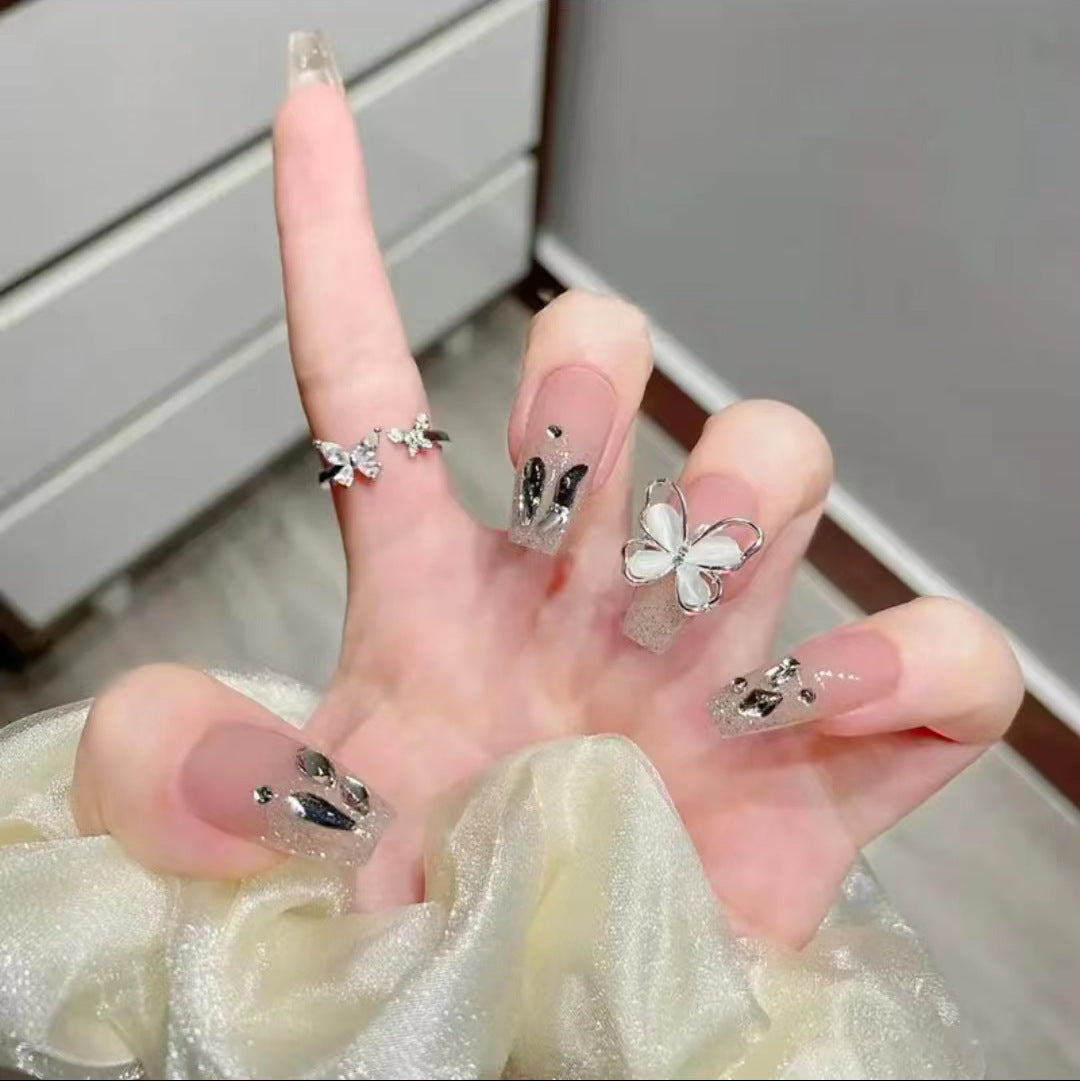 Kunstvolle Nagelkunst mit Glitzer- und Schmetterlingselementen Brehn