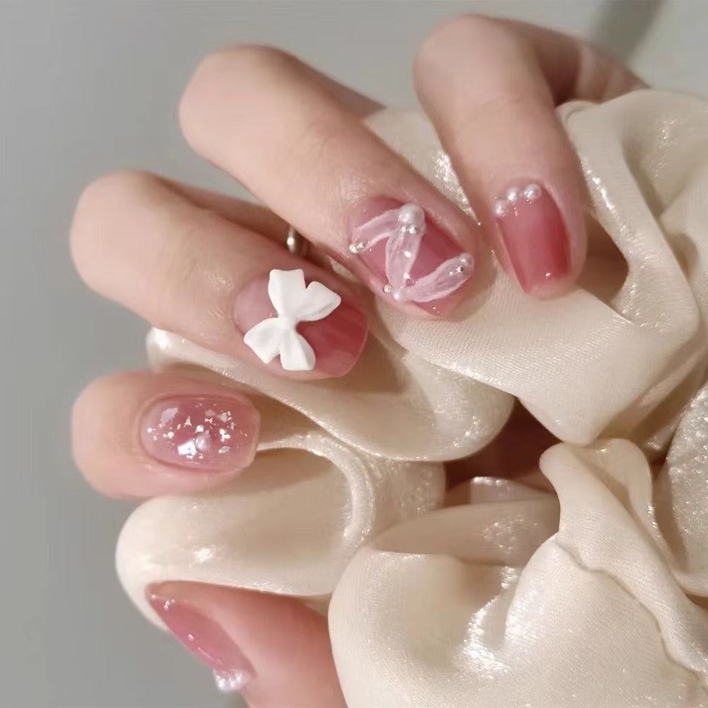 Glamouröse Nagelkunst mit Perlen- und Schleifenakzenten Brehn