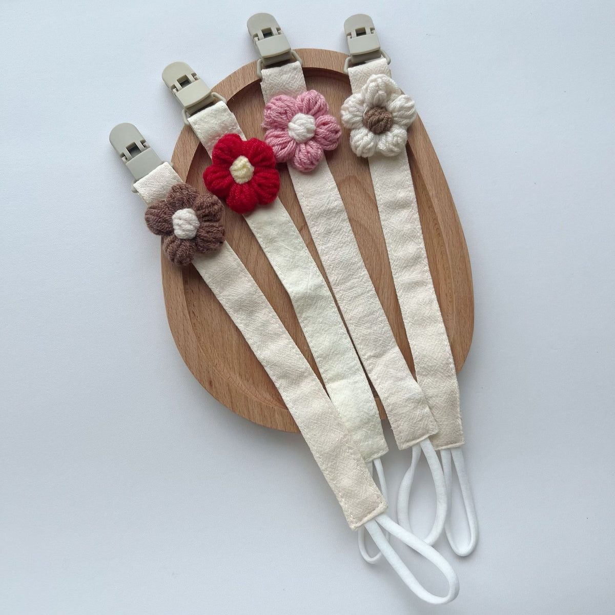 Handgemachter Baumwoll-Schnullerclip mit Gingham-Gurt und gestrickter Blume