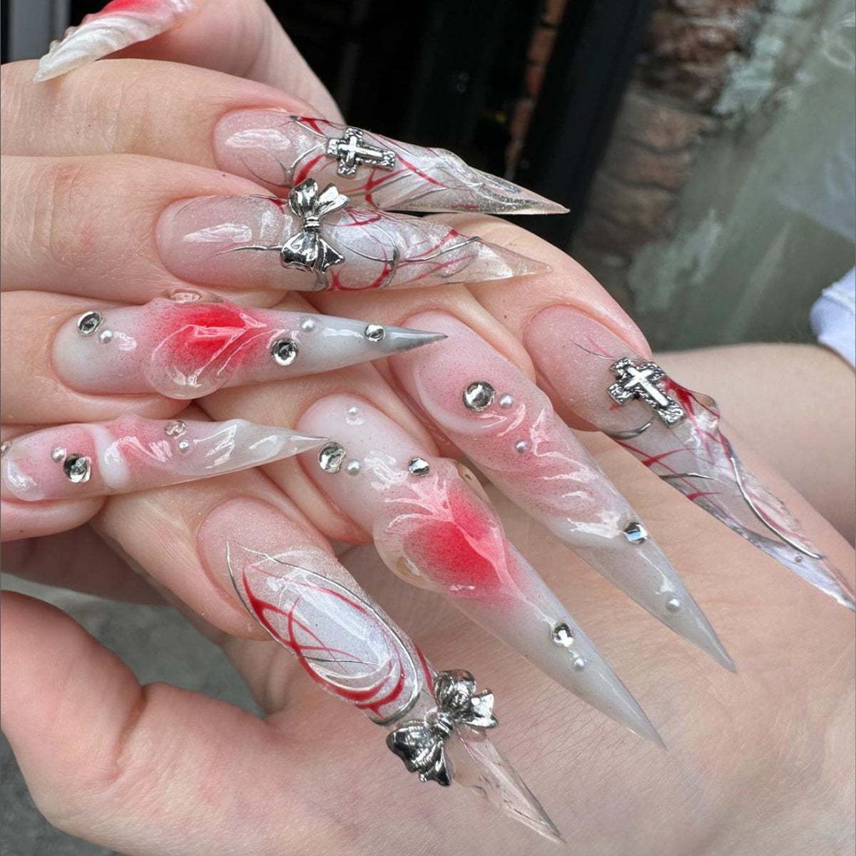 Kunstvolle Stiletto-Nägel mit eleganter floralem Akzent und Glitzerverzierungen Brehn